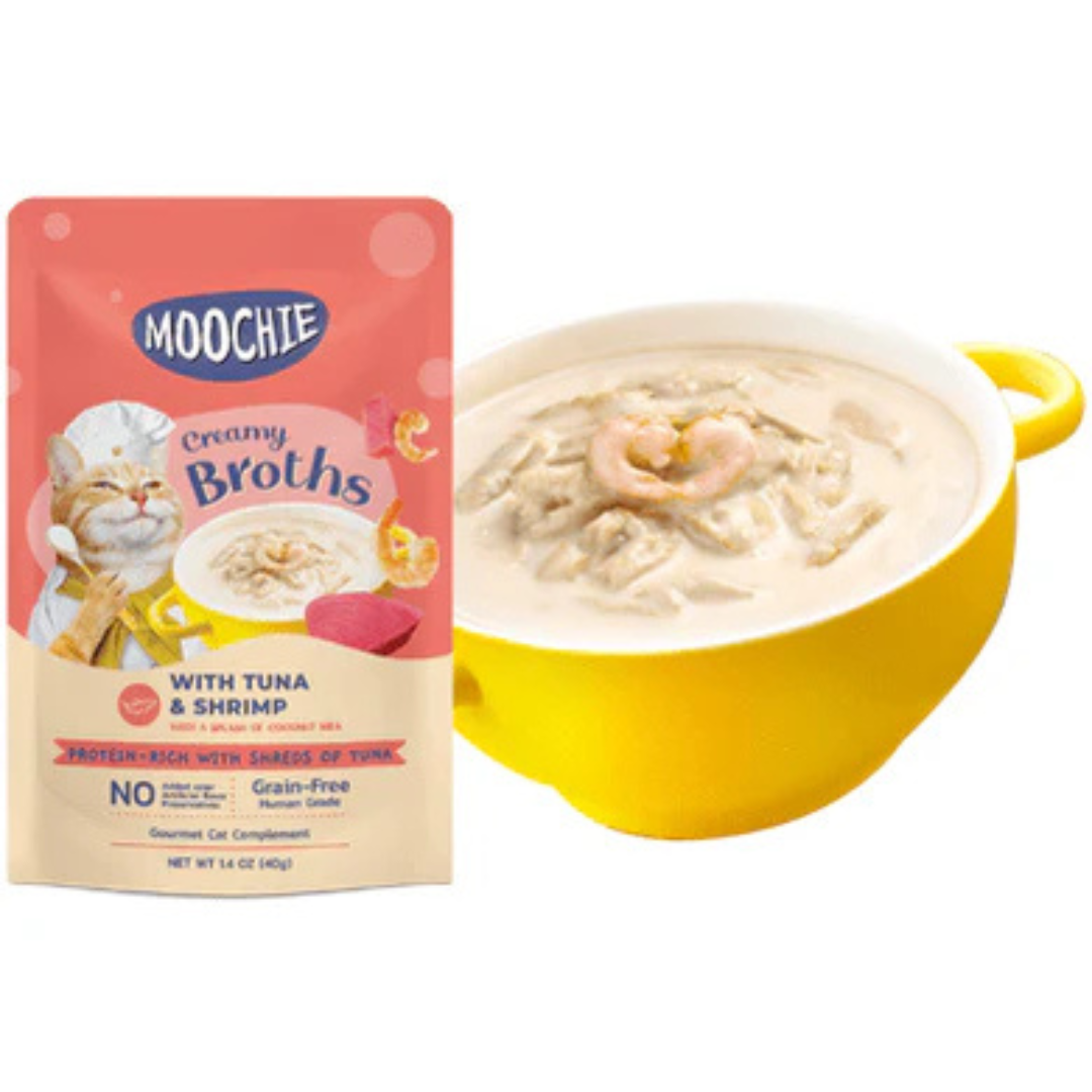 Packaging of Moochie Creamy Broths with Tuna & Shrimp. The package is predominantly pink with images of tuna and shrimp, and the product is shown in a yellow bowl.